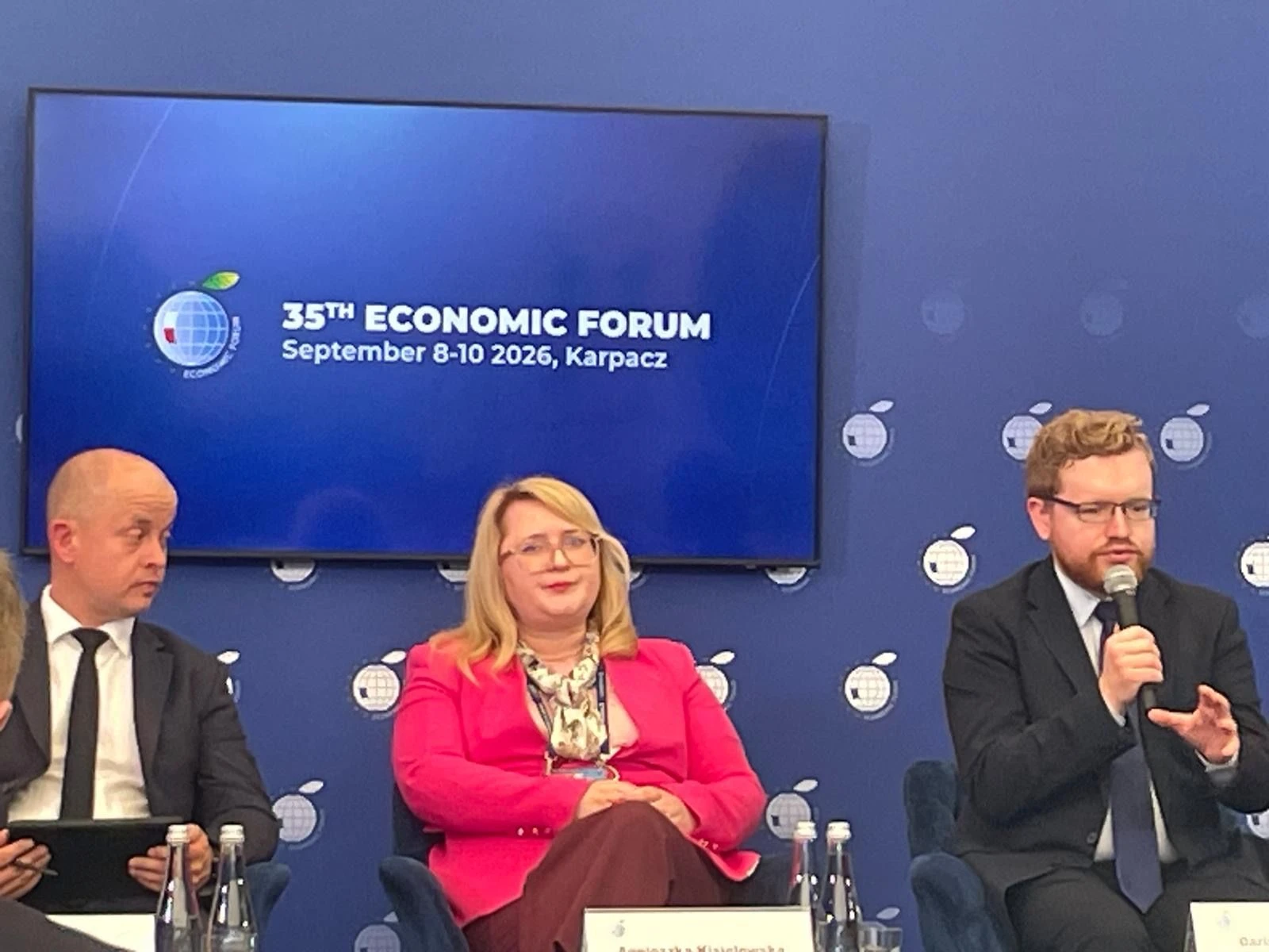 Panel dyskusyjny 35. Forum Ekonomicznego w Karpaczu, na ekranie nazwa i termin wydarzenia, po prawej panelista mówi do mikrofonu.